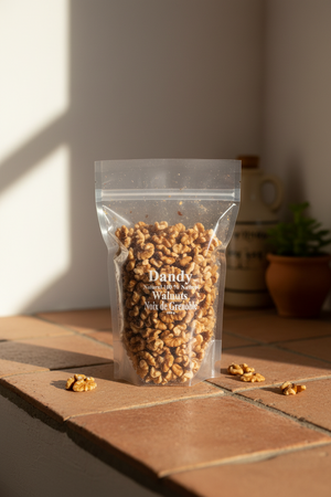 A clear plastic bag filled with raw walnuts, with the brand 'Dandy' printed on the front.